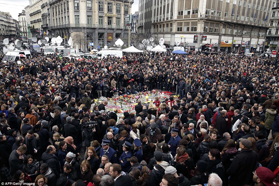United in grief: The people of Brussels stand together during a minute of silence around a makeshift memorial at Place de la Bourse at midday today