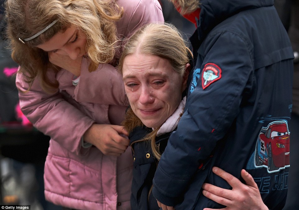 Gripped by grief: A heartbroken mother is comforted by her two children as she pays her respects to the 34 terror attack victims in Brussels this afternoon